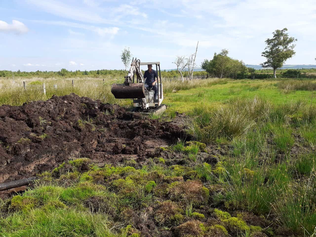 wildlife pond creation in progress with digger removing turf and soil